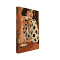 Woman in a cream blouse with black polka dots holding an espresso cup at a terracotta café table beside leafy plants.