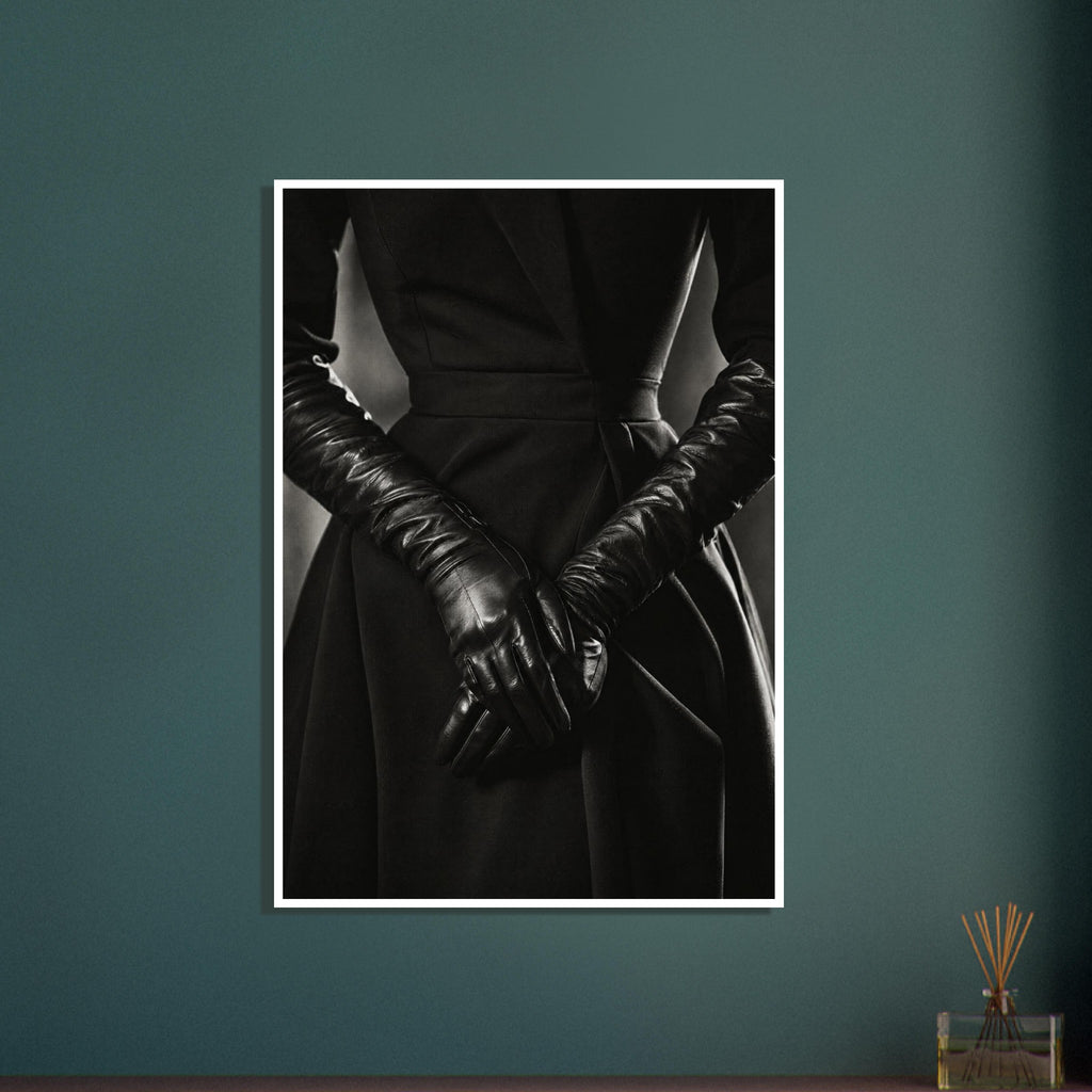 Overlapping hands in long black leather gloves against a dark fitted outfit, photographed in black and white.