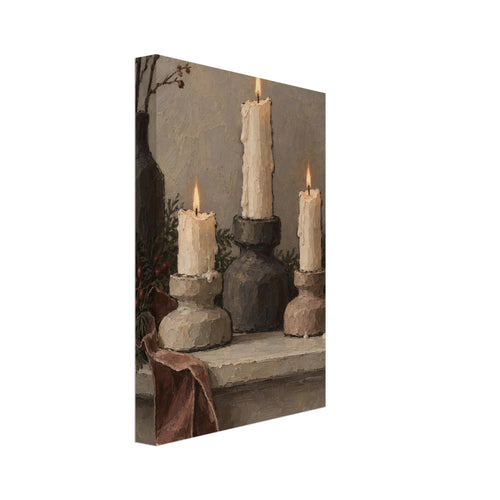 Three lit ivory candles on chunky holders, with a dark vase, branches, greenery and a draped burgundy ribbon.