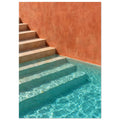 Stone steps descending into turquoise pool water beside a terracotta wall, with sunlight rippling across submerged stairs.