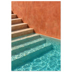 Stone steps descending into turquoise pool water beside a terracotta wall, with sunlight rippling across submerged stairs.