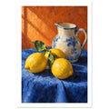 Three yellow lemons with green leaves beside a cream and blue floral jug on blue cloth against an orange background.