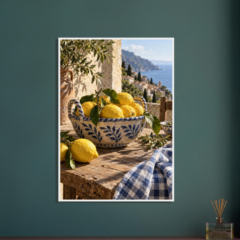 Lemons in a blue-and-white bowl on a wooden table, with olive branches, checked cloth and a coastal village beyond.