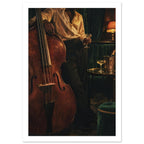 Double bass beside a figure holding a stemmed glass, with dark green seating, a drinks table and a glowing lamp.