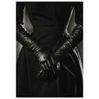Overlapping hands in long black leather gloves against a dark fitted outfit, photographed in black and white.