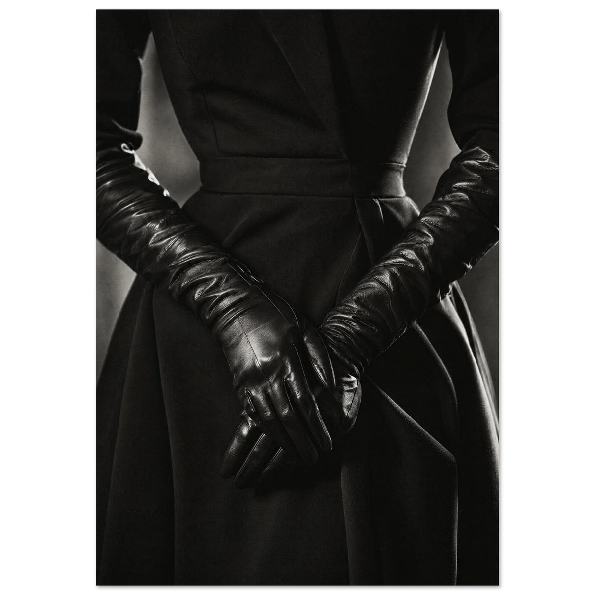 Overlapping hands in long black leather gloves against a dark fitted outfit, photographed in black and white.