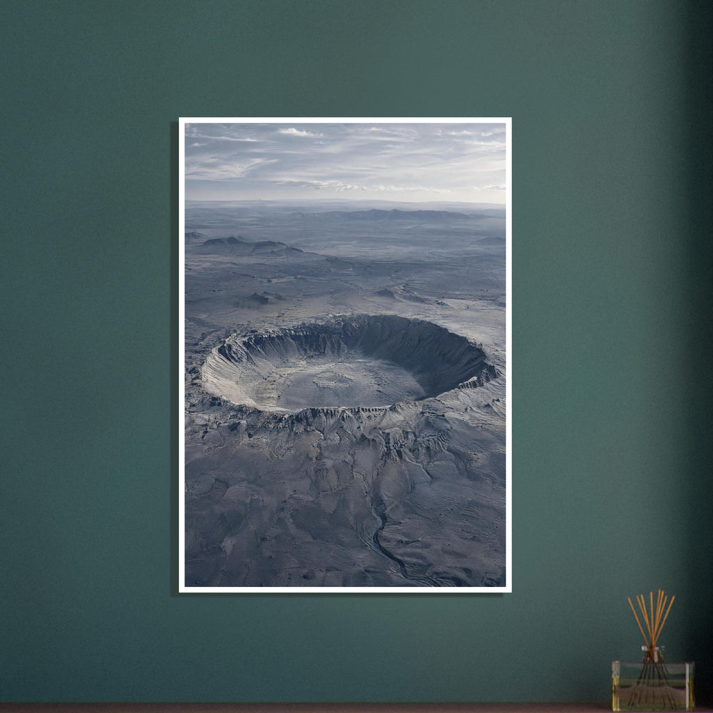 Large circular crater in a blue-grey desert plain, with rugged slopes, distant hills and a cloudy sky.