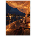 Yacht deck at night with glowing draped fabric, a candlelit table and a glass overlooking an illuminated harbour.