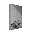 Bicycle leaning against a textured wall, with diagonal sunlight and long shadows across the wall and pavement.