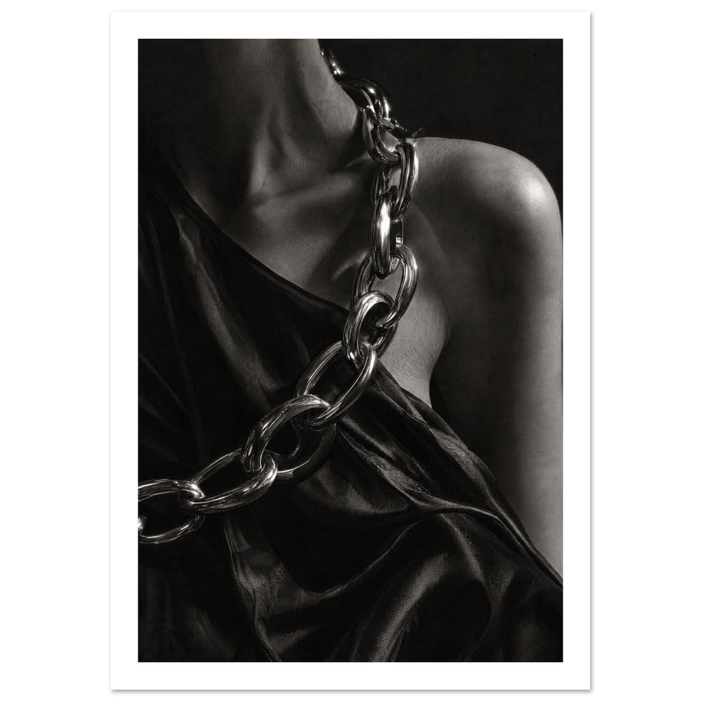 Oversized polished chain links cross dark, lustrous fabric beside a bare shoulder and neckline in black and white.