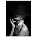 Woman in a wide-brim black hat hiding her eyes, with a hand near her chin and a white collar, in black and white.
