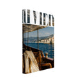 Riviera lettering above a boat scene with a wooden chair, cream scarf, sunglasses and blue sea facing waterfront buildings.