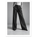 Cropped figure in dark wide-leg trousers, a white ribbed top and pointed shoes, standing with hands in pockets.