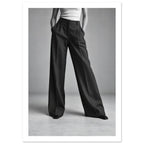 Cropped figure in dark wide-leg trousers, a white ribbed top and pointed shoes, standing with hands in pockets.