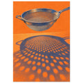 Blue kitchen sieve against an orange background, casting a large perforated shadow across the surface below.