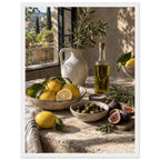 Lemons, olives, figs and a bottle of oil on a stone table beside a ceramic jug of leafy branches and a sunlit window.