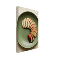 Red-skinned apple slices arranged in a curve on a green plate, photographed from above on cream fabric.