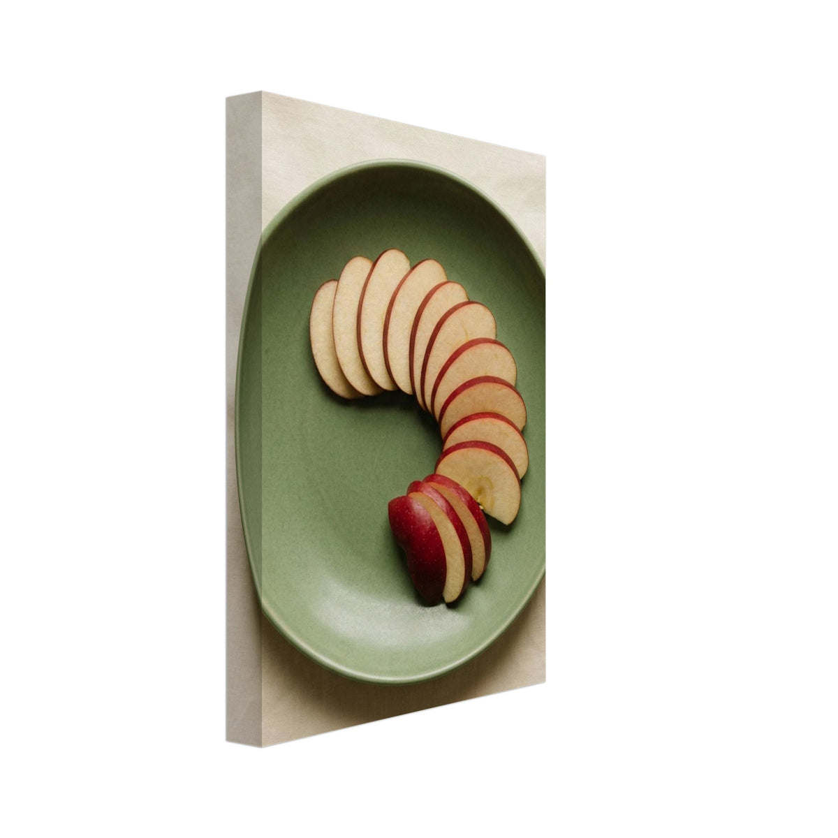 Red-skinned apple slices arranged in a curve on a green plate, photographed from above on cream fabric.