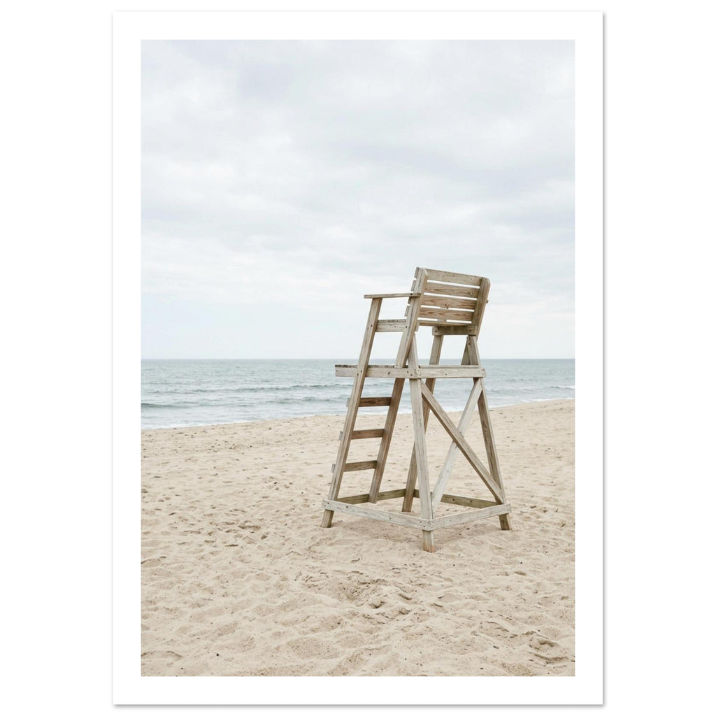 Empty wooden lifeguard chair on pale sand beside gentle sea waves beneath an overcast sky.