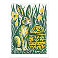 Green and yellow hare beside a floral-patterned Easter egg, surrounded by tall grass and yellow flowers on off-white.