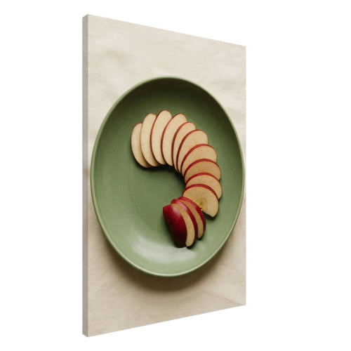 Red-skinned apple slices arranged in a curve on a green plate, photographed from above on cream fabric.