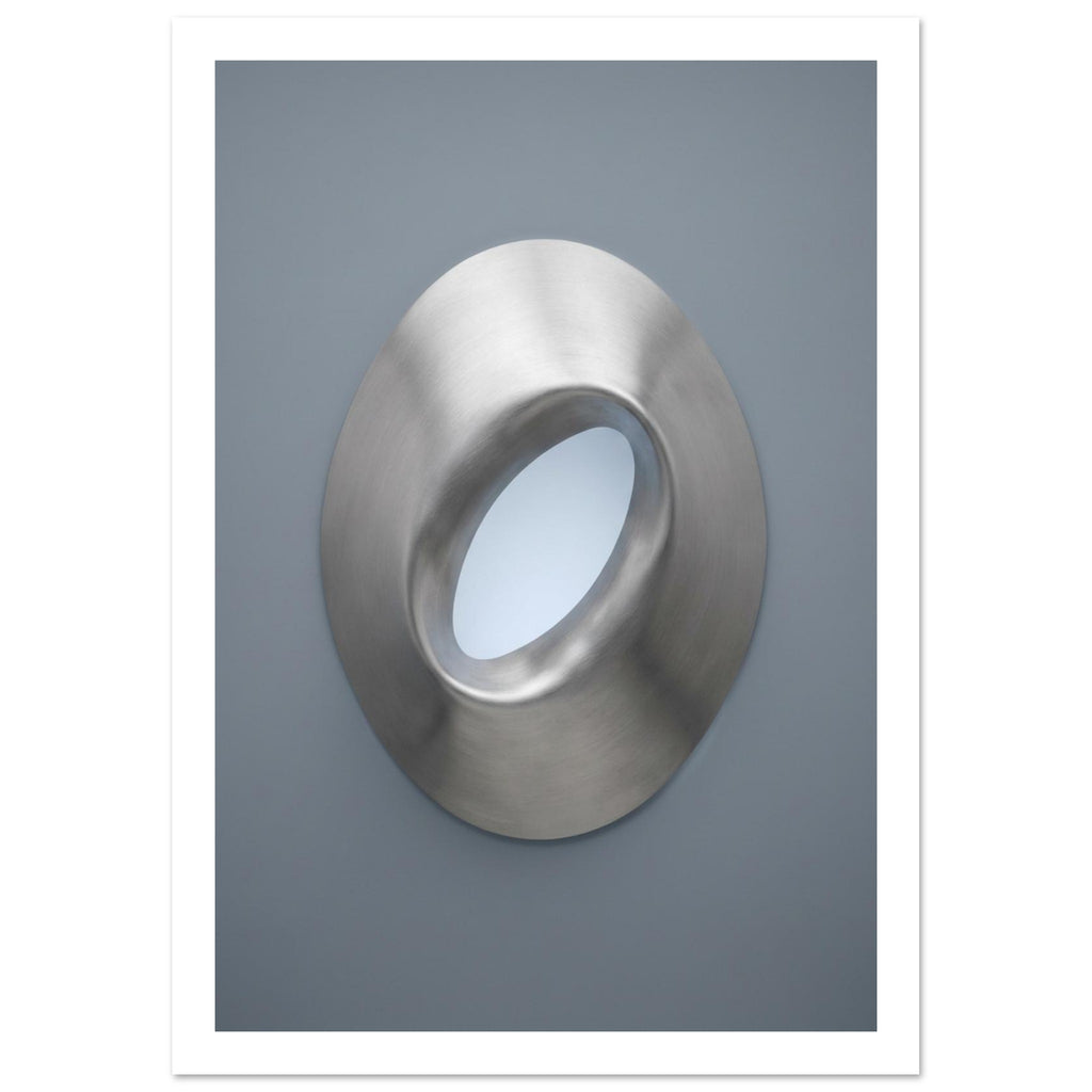 Brushed silver oval ring with a tilted opening, soft highlights and shadows against a blue-grey background.