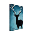Black deer silhouette with cream blossoms on its antlers, against a textured teal backdrop with white dots and grasses.