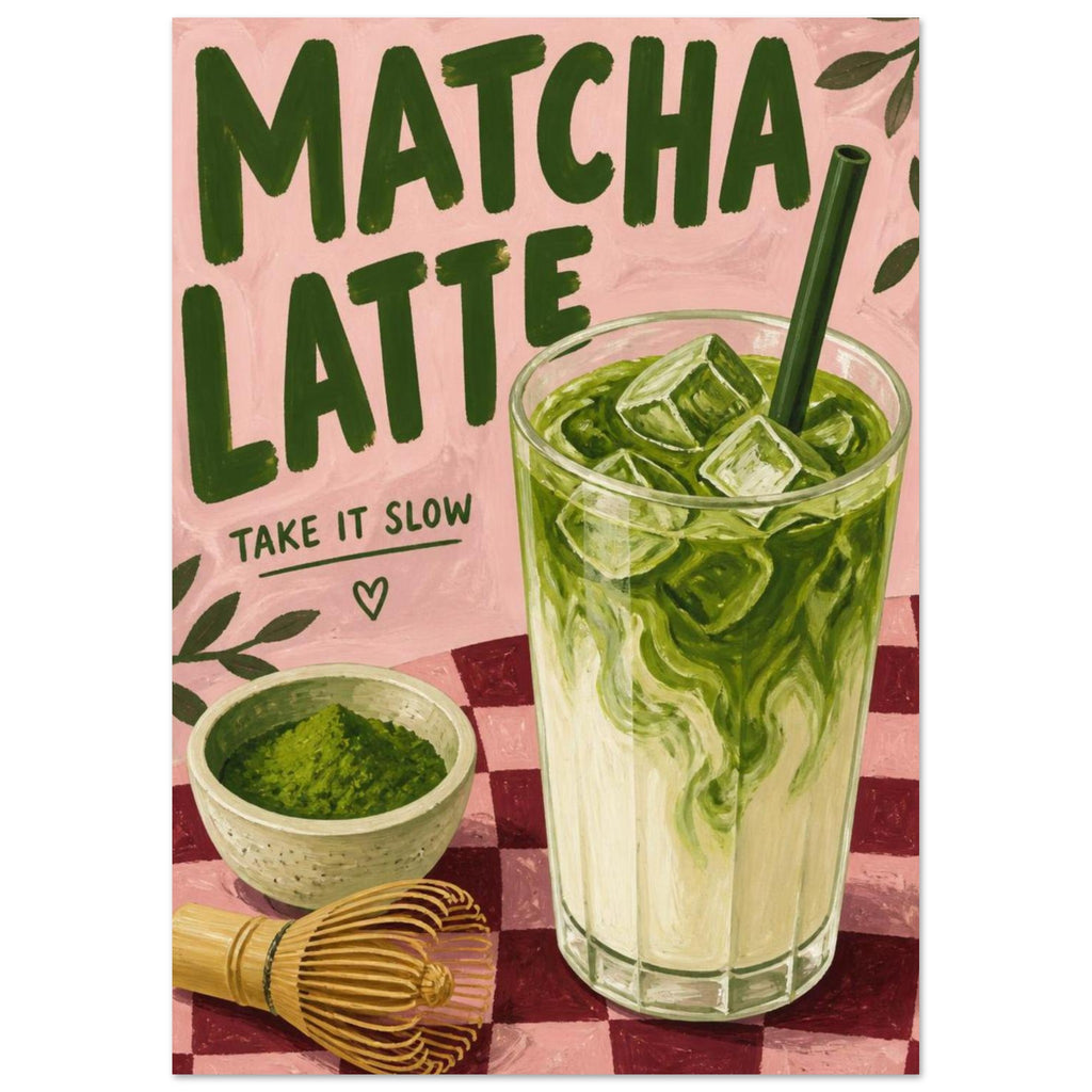 Iced matcha latte with a powder bowl and bamboo whisk on a pink checked surface beneath ‘Matcha Latte’ lettering.