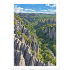 Jagged grey stone pinnacles rising through dense green forest beneath a blue sky with scattered white clouds.