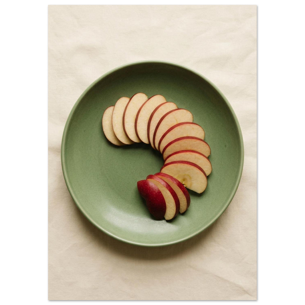 Red-skinned apple slices arranged in a curve on a green plate, photographed from above on cream fabric.