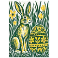 Green and yellow hare beside a floral-patterned Easter egg, surrounded by tall grass and yellow flowers on off-white.