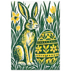 Green and yellow hare beside a floral-patterned Easter egg, surrounded by tall grass and yellow flowers on off-white.