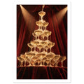 Champagne cascading down a tower of coupe glasses, lit by warm spotlights against deep burgundy curtains.