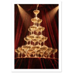 Champagne cascading down a tower of coupe glasses, lit by warm spotlights against deep burgundy curtains.