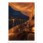Yacht deck at night with glowing draped fabric, a candlelit table and a glass overlooking an illuminated harbour.