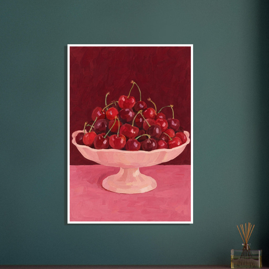 Red and burgundy cherries in a pale pink pedestal bowl on a pink tabletop against a deep red painted background.