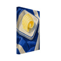 Butter curl in a cream dish with a blue rim, beside a silver-coloured knife on blue and cream striped fabric.