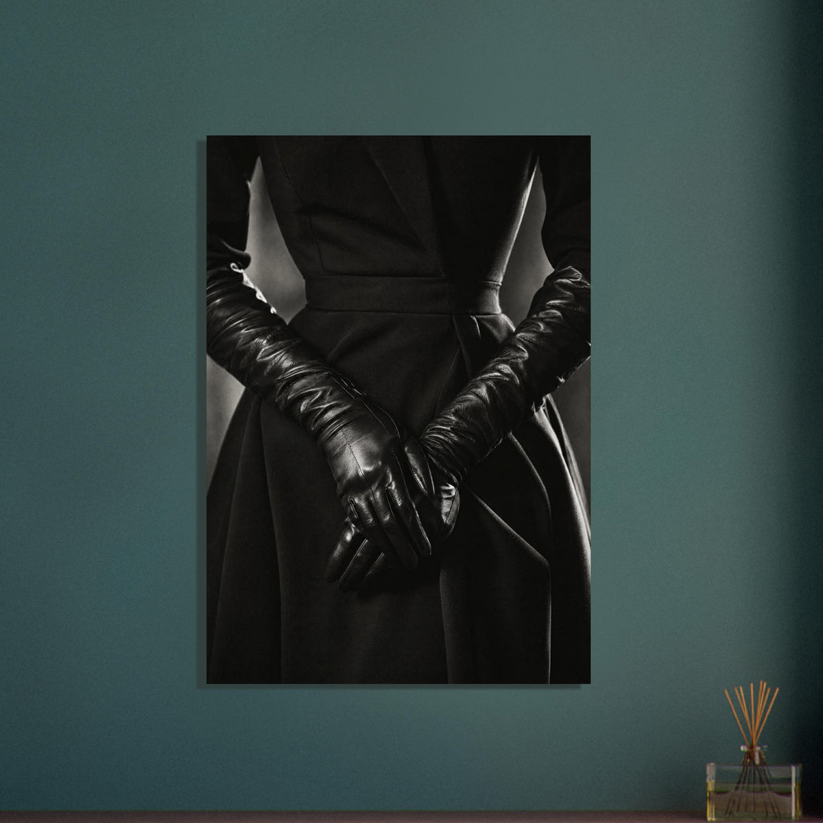 Overlapping hands in long black leather gloves against a dark fitted outfit, photographed in black and white.