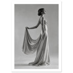 Woman in profile wearing a floor-length gown, holding draped fabric behind her against a plain grey background.