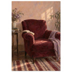 The Reading Chair painting showing a burgundy armchair with an open book, a cropped striped rug and afternoon light.