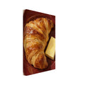 Golden croissant and a rectangular pat of butter on a burgundy plate, painted with textured brushstrokes on cream.