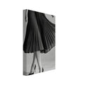 Cropped figure in a flowing black pleated skirt and pointed high heels, with crossed legs against a grey background.