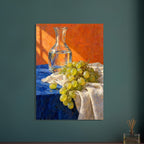 Green grapes on cream fabric beside a glass carafe of water, with a blue tabletop and textured orange background.