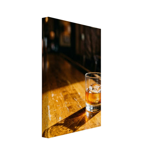 Tumbler of amber drink with ice on a sunlit wooden bar, casting a long shadow against a dark, blurred interior.